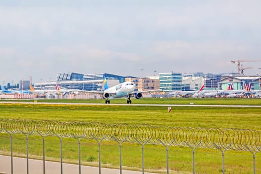 Stuttgart, Germany - April 29, 2017: Airbus airplane A320 from Condor at takeoff from runway - airport Stuttgart terminal in background - green meadow with fence in front