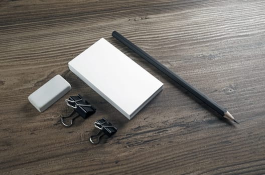 Photo of blank business cards, pencil and eraser on wooden background. Blank stationery set.