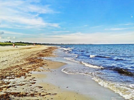 Beach in Marielyst, denmark with ocean waves of baltic sea and blue sky