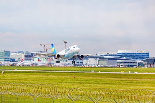 Stuttgart, Germany - April 29, 2017: Airbus airplane A320 from Condor at takeoff from runway - airport Stuttgart terminal in background - green meadow with fence in front