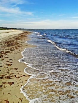 Beach in Marielyst, denmark with ocean waves of baltic sea and blue sky
