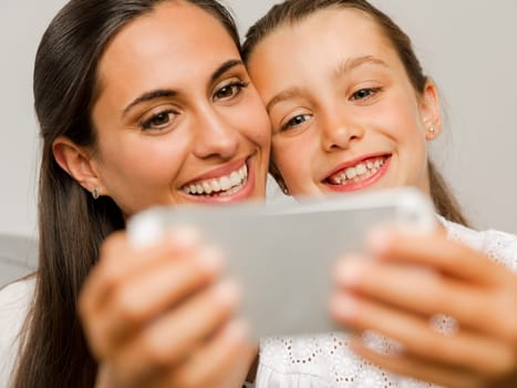 Beautiful Mom and Daughter at home, showing something on the phone