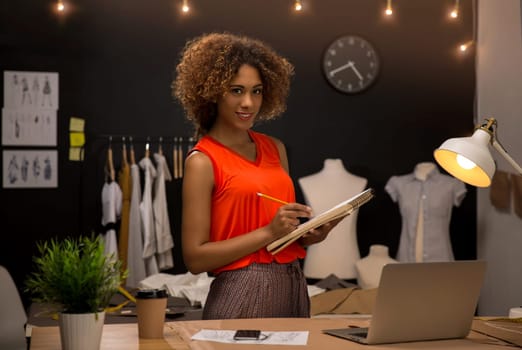 Portrait of a young fashion designer working on her atelier