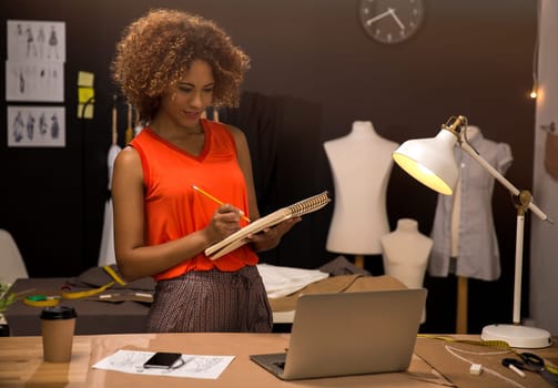 Portrait of a young fashion designer working on her atelier