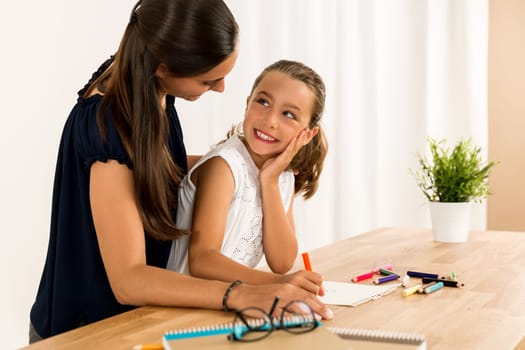 Mom teaching Daughter working with a a laptop at home