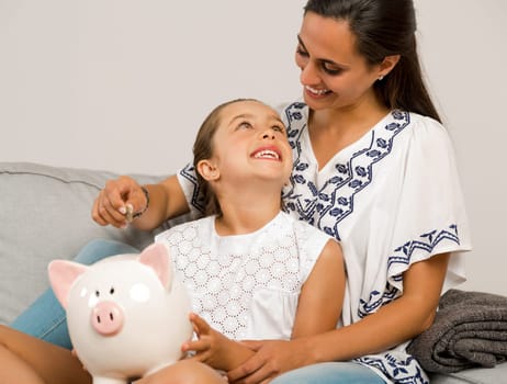 Mother and daughter with a piggy bank for her future savings