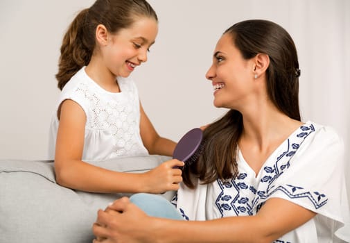Litle girl helping mother brushing her hair