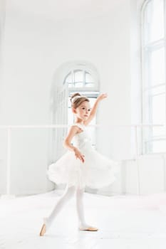 Little ballerina girl in a tutu. Adorable child dancing classical ballet in a white studio. Children dance. Kids performing. Young gifted dancer in a class. Preschool kid taking art lessons.