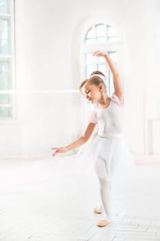 Little ballerina girl in a tutu. Adorable child dancing classical ballet in a white studio. Children dance. Kids performing. Young gifted dancer in a class. Preschool kid taking art lessons.