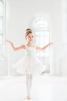 Little ballerina girl in a tutu. Adorable child dancing classical ballet in a white studio. Children dance. Kids performing. Young gifted dancer in a class. Preschool kid taking art lessons.