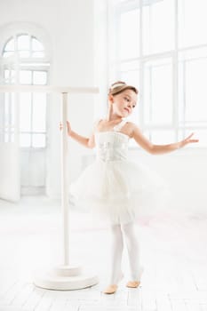 Little ballerina girl in a tutu. Adorable child dancing classical ballet in a white studio. Children dance. Kids performing. Young gifted dancer in a class. Preschool kid taking art lessons.