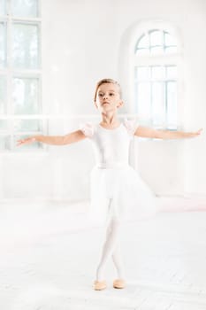 Little ballerina girl in a tutu. Adorable child dancing classical ballet in a white studio. Children dance. Kids performing. Young gifted dancer in a class. Preschool kid taking art lessons.