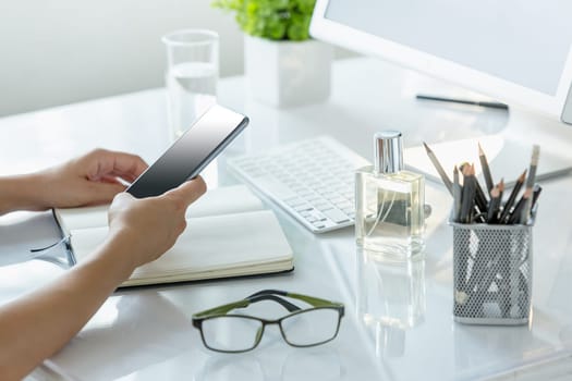The female hands using smart phone while working on computer at modern office interior, businesswoman concept
