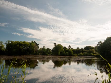 beautiful summer lake scene outside trees clouds reflected in water  England  UK