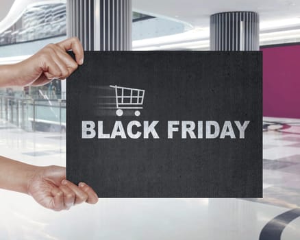 Hand holding signboard with shopping cart and Black Friday text. Black friday concept