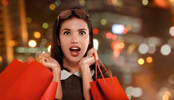 Happy asian woman with red shopping bag celebrating Black Friday on the mall
