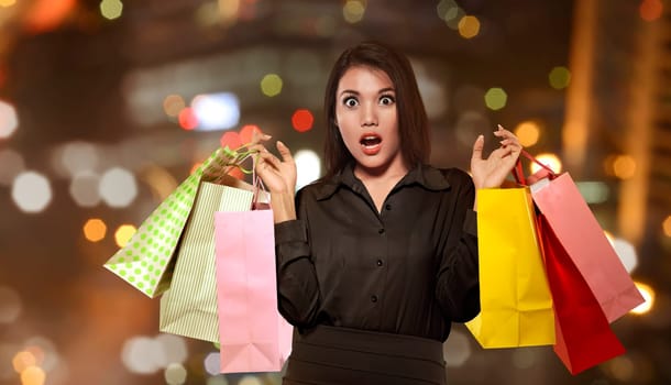 Excited asian woman holding colorful paper bag celebrating Black Friday on the mall
