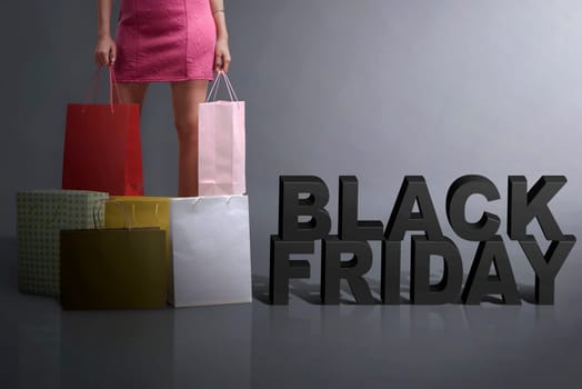 Young shopper holding shopping bag standing with Black Friday text over black background