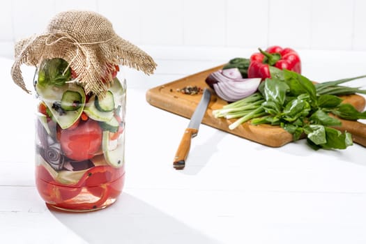 Canned tomatoes and fresh tomatos and other cut vegetables on white background