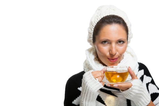 Young brunette woman with white wool lyane drinks a cup of tea to warm up isolated on white background
