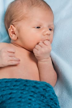 Newborn baby baby wrapped in a blue wool blanket naked as a close-up