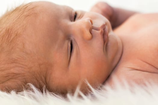 Close-up of a newborn baby lying on a fluffy white blanket