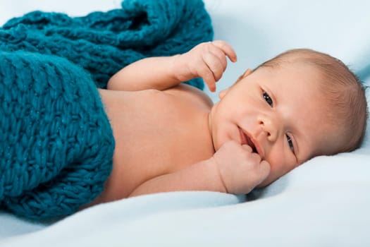 Newborn baby baby wrapped in a blue wool blanket naked as a close-up