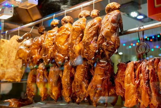 Detail of Chinese restaurant with traditional crispy ducks hanging on foggy display window in London's Chinatown at night.
