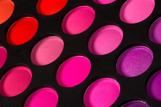 Eye shadow palette with pink colors on black background.