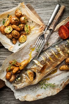 Baked sea bass with roasted potatoes on wooden table