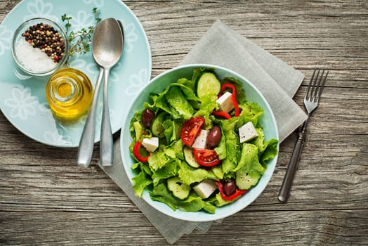 Green Salad with cheese and fresh vegetables on wooden background. Greek salad.