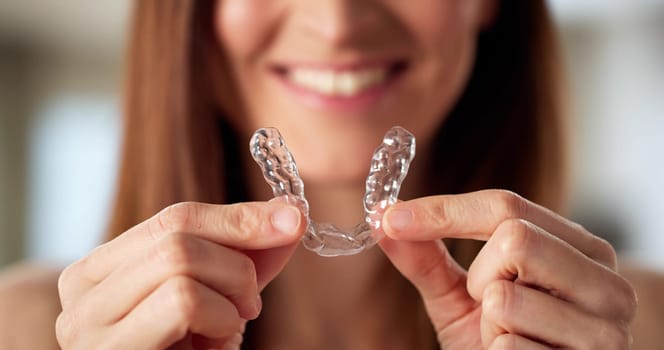 Dentist fitting clear aligner dental night guard for woman's teeth.