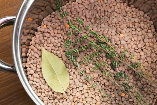 Lentils, thyme and bay leaf in pot, ready for cooking.