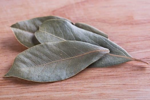Dried bay leaves on wooden board.