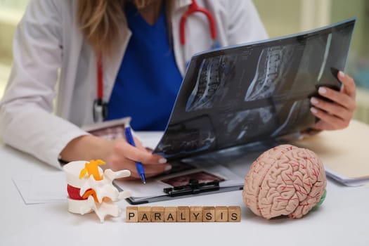 A skilled medical professional is reviewing Xrays and models related to paralysis treatment and care