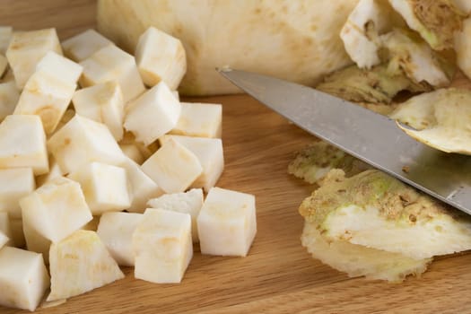 Celeriac cubes with peels and knife.