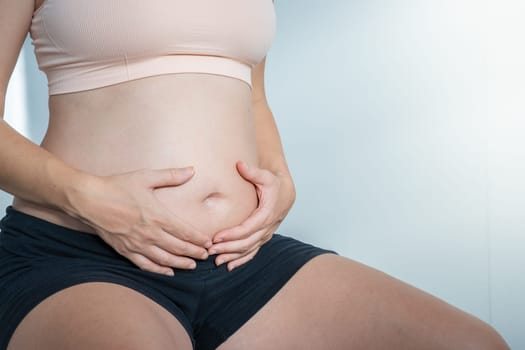 A serene portrayal of a pregnant woman gently cradling her belly, showcasing the beauty of motherhood.