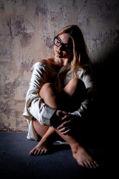 A thoughtful woman is seated against a beautifully textured wall, radiating a sense of calm and introspection
