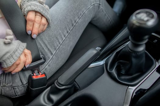 A woman fastens her seatbelt in a modern car, highlighting the importance of safety while traveling
