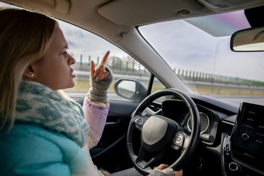 A woman confidently gestures while driving on a busy highway, showcasing her carefree attitude and modern lifestyle
