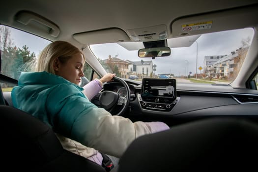 A woman is intensely focused on her driving as she navigates the city in a stylish car with modern interior design