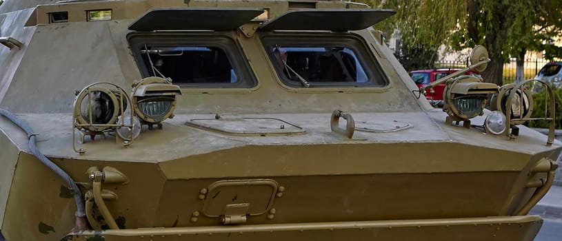 A military armored vehicle is stationary, showcasing its rear design and equipment under daylight conditions.