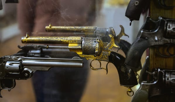 Numerous vintage revolvers are showcased in a gun shop, highlighting their unique designs and polished finishes.