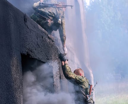 Soldiers from special forces maneuver through an obstacle course amidst smoke, showcasing strength and agility in a rigorous training exercise.