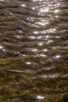 A beautifully serene and captivating view of shimmering water ripples illuminated by warm sunlights glow