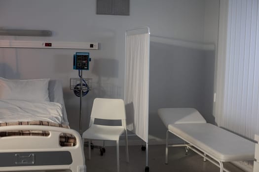 A meticulously sterile hospital room that includes a patient bed, necessary medical equipment, and seating areas