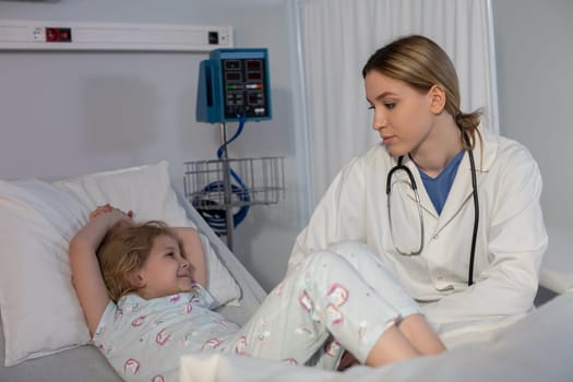 A dedicated and compassionate doctor in a hospital room positively interacts with a young patient, providing care