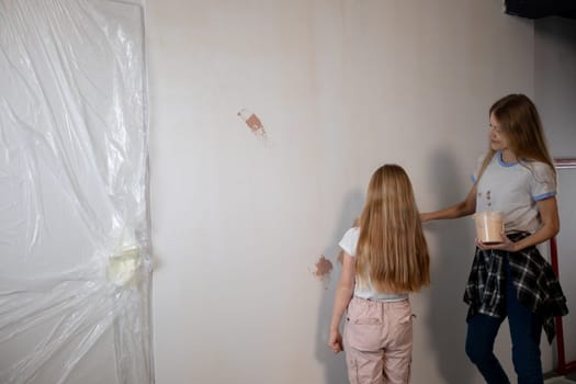A loving mother and her young daughter are engaging in a delightful and fun painting project in their cozy home setting