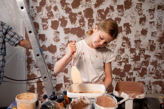 A young girl joyfully painting a colorful wall while actively engaged in an exciting home renovation project