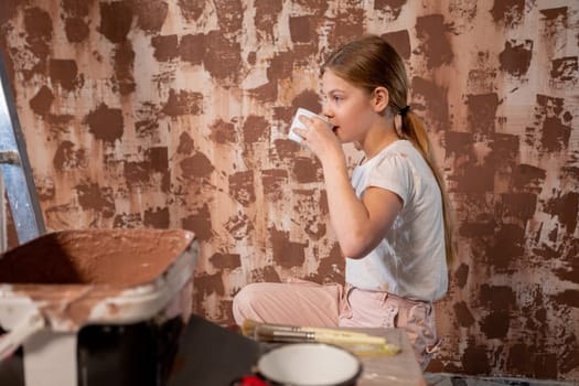 A cheerful girl sips a colorful drink while engaged in a home project, showcasing her creativity and spirit